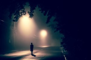 Pessoa solitária em uma rua escura e com neblina