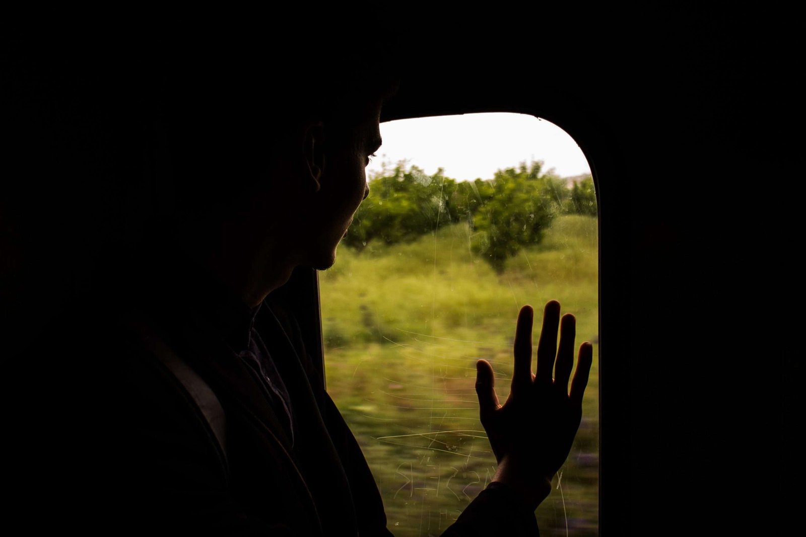 Homem jovem em um trem com a mão encostada no vidro