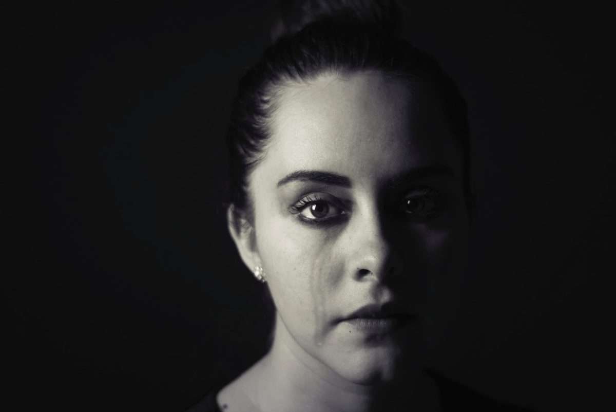 Foto em preto e branco do rosto de uma mulher com uma lágrima escorrendo do seu olho direito