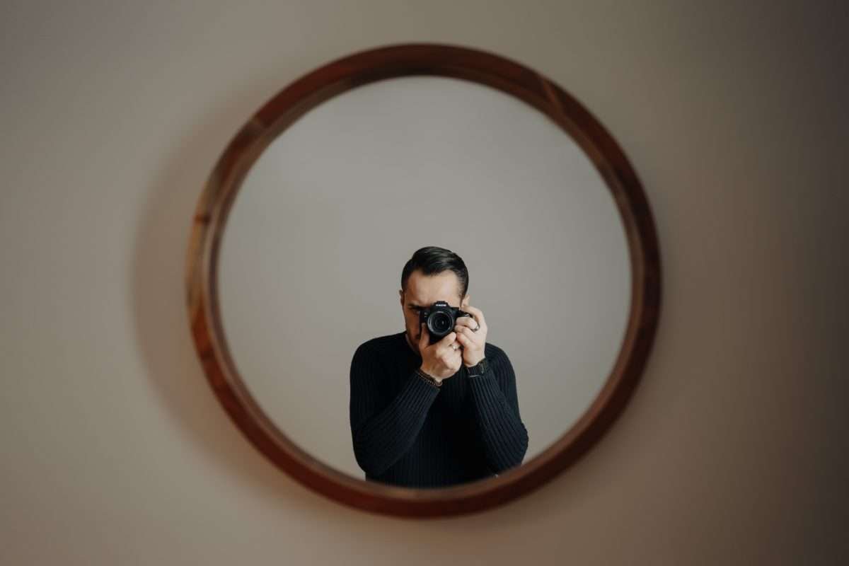 Homem se fotografando em frente ao espelho