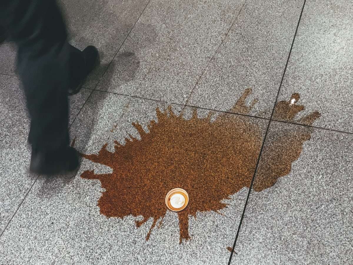 Copo do café derramado no piso de mármore