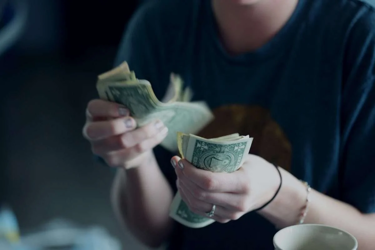 Mulher com camisa azul contando notas de 1 dólar