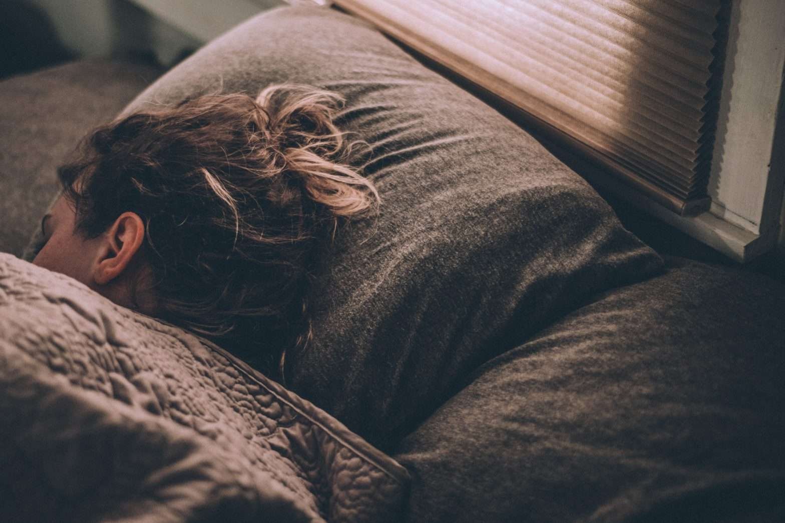 Mulher dormindo em uma cama de cor cinza