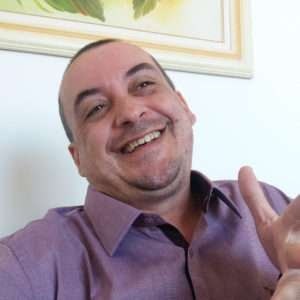 Psicólogo Emilson Silva com camisa roxa e rindo