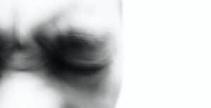 Foto em preto de branco da metade superior direita de um rosto desfocado