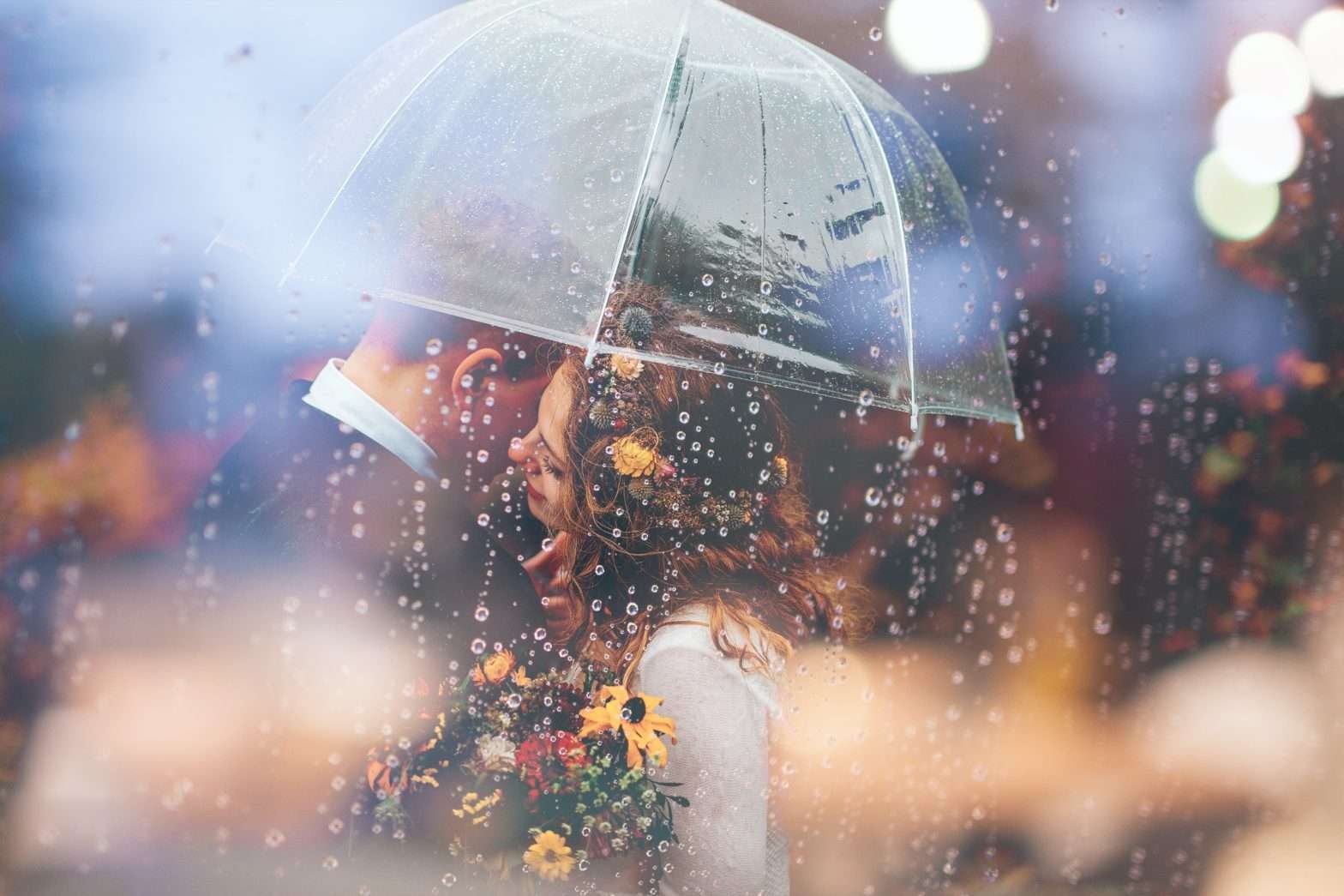 Casal abraçado embaixo de um guarda-chuva transparente