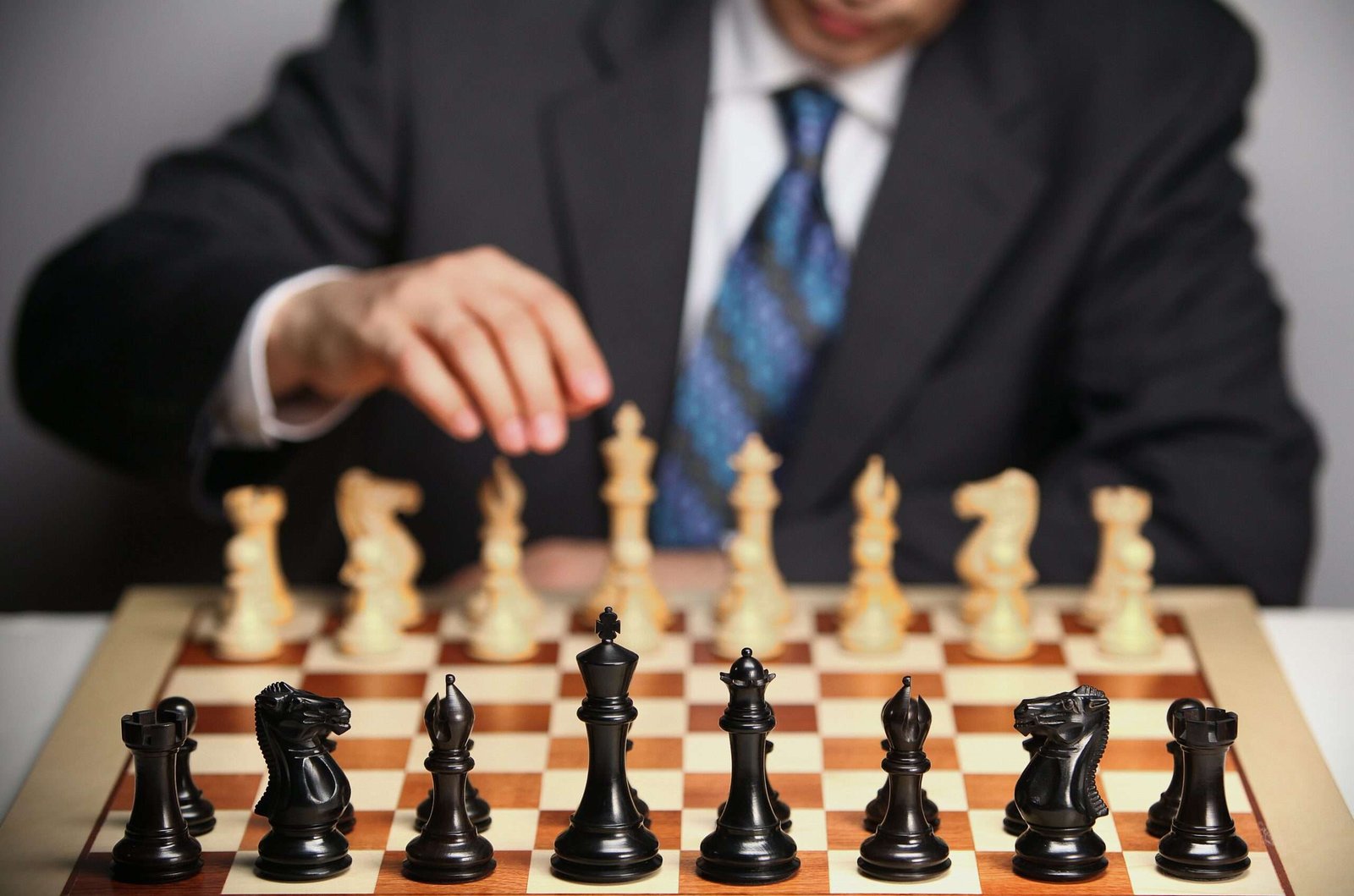 Homem de terno e gravata jogando xadrez