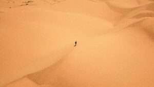 Homem caminhando de forma solitária por um deserto