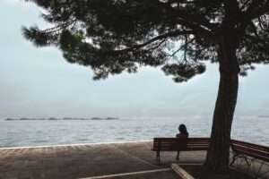 Mulher solitária sentada em um banco na beira do mar