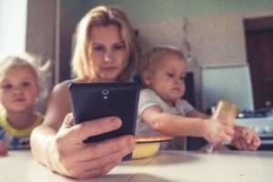 Uma mulher com dois filhos e olhando a tela de um celular