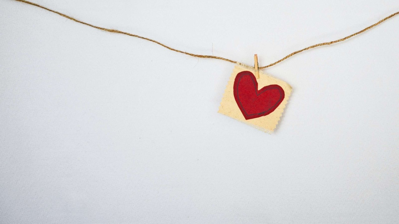 Coração feito de feltro pendurado em um barbante por um grampo de roupas