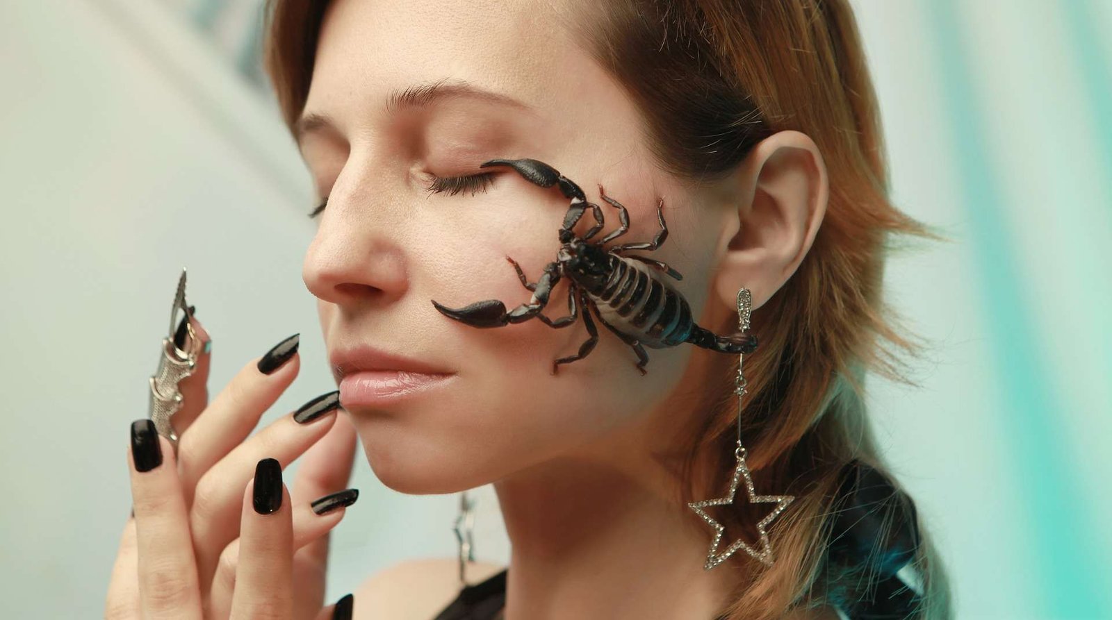 Mulher com unhas compridas e com um escorpião em seu rosto