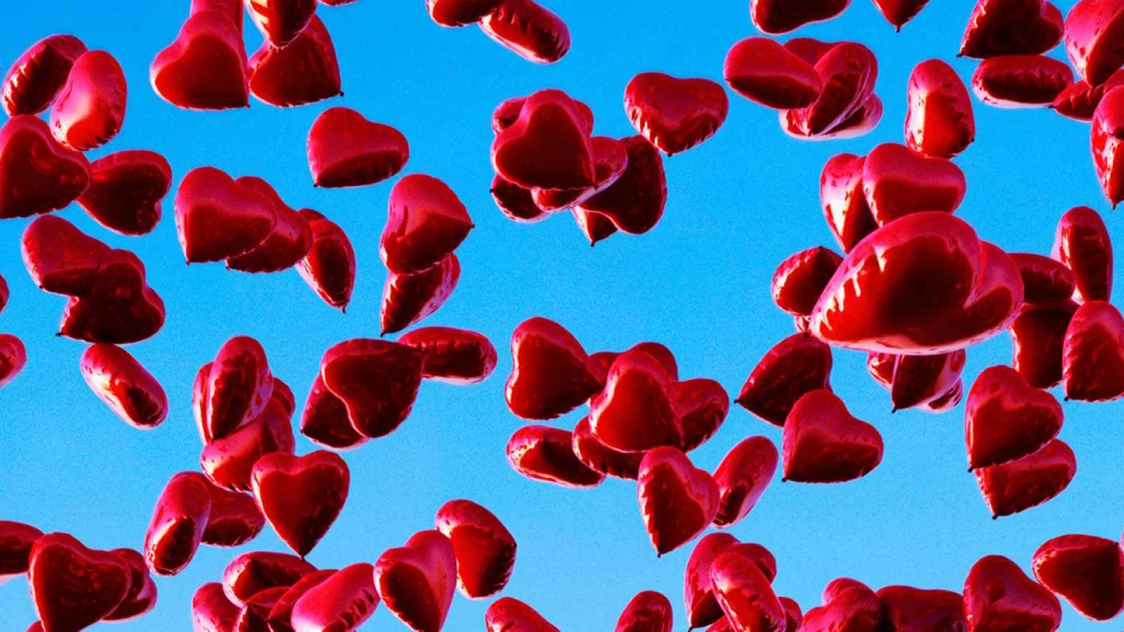 Vários balões em formato de coração voando pelo céu