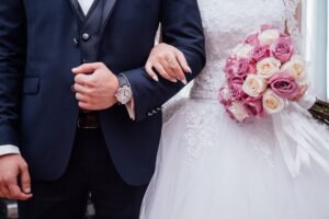 Homem de terno de braços dados à uma mulher vestida de noiva