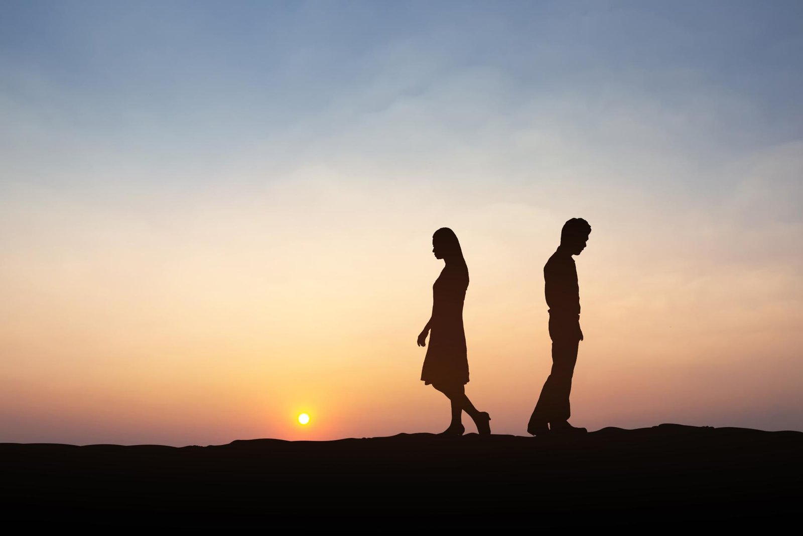 Silhueta de um homem e uma mulher se afastando durante o pôr-do-sol