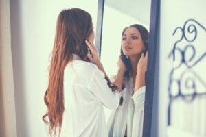 Mulher de cabelos longos se olhando em um espelho