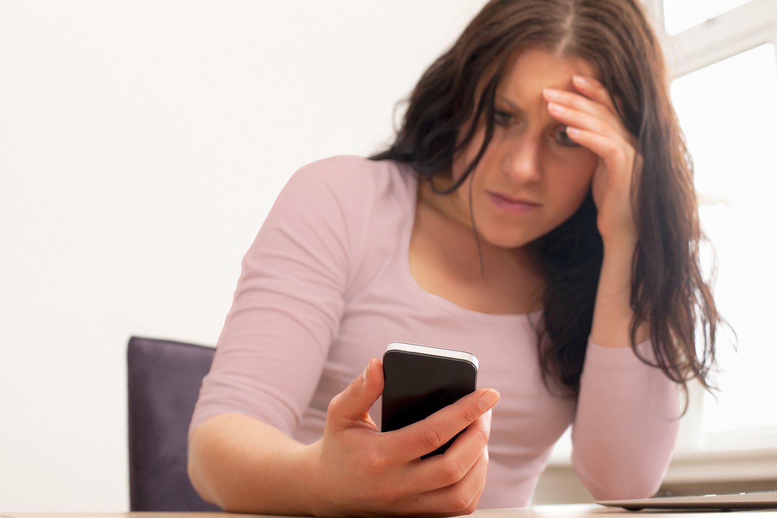 Uma mulher com expressão de preocupação olhando para a tela do celular
