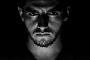 Foto em preto e branco da face de um homem com um olhar maligno