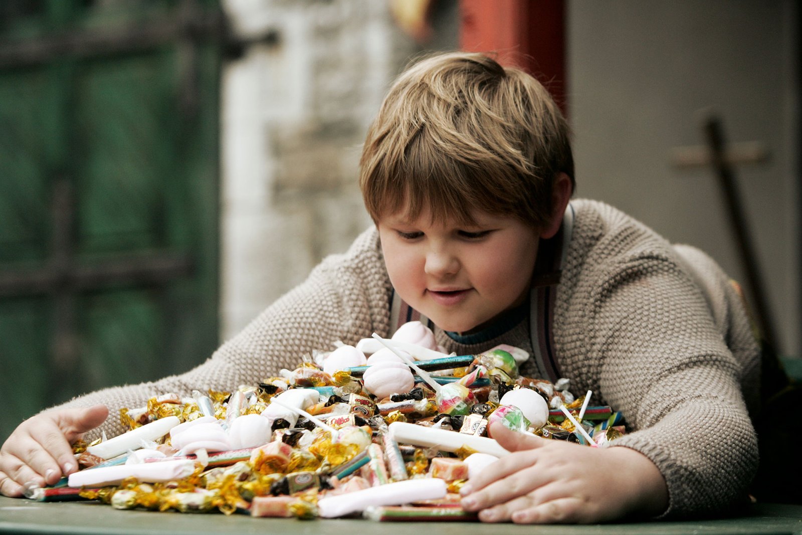 Um menino obeso abraçando uma grande quantidade de doces