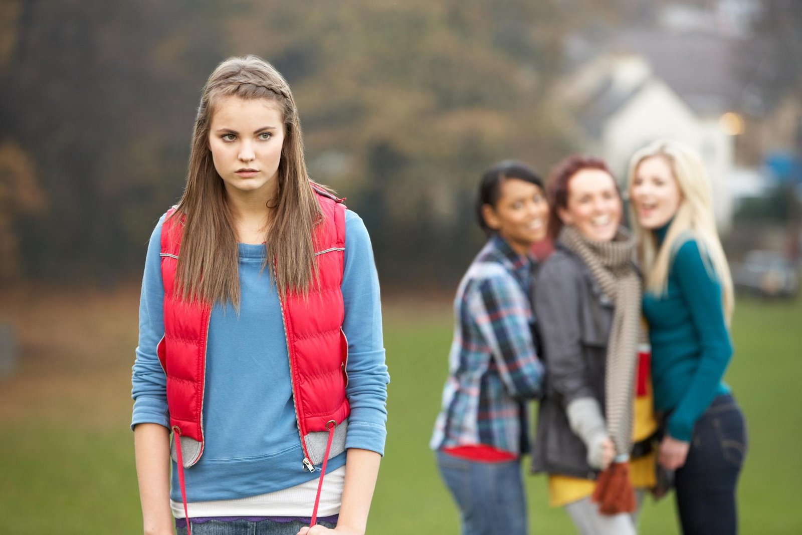 Uma jovem de colete vermelho sendo excluída do seu grupo de amigas