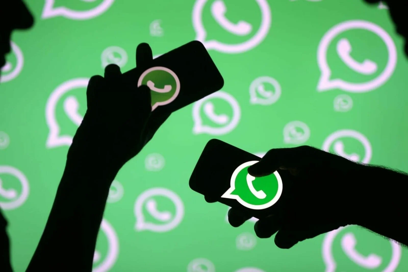 Silhueta de duas pessoas segurando celulares e diversos ícones do whatsapp ao fundo