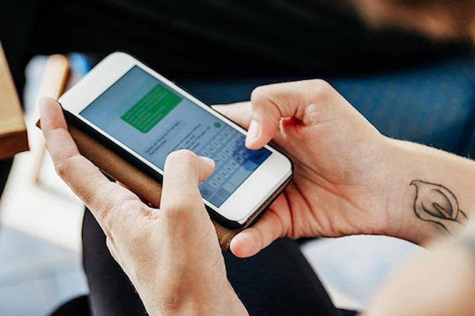 Mãos segurando um celular enquanto enviam uma mensagem de texto