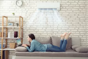 Uma mulher deitada no sofá, diante de um notebook e escolhendo um Psicólogo online