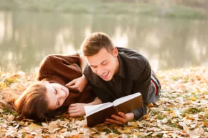 Um homem em um relacionamento rebote lendo um livro com uma mulher na beira de um lago